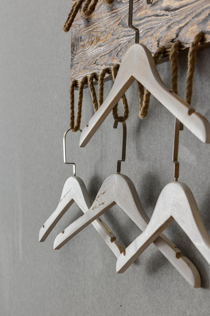 A minimalist arrangement of wooden hangers hanging from rustic rope on a wall.
